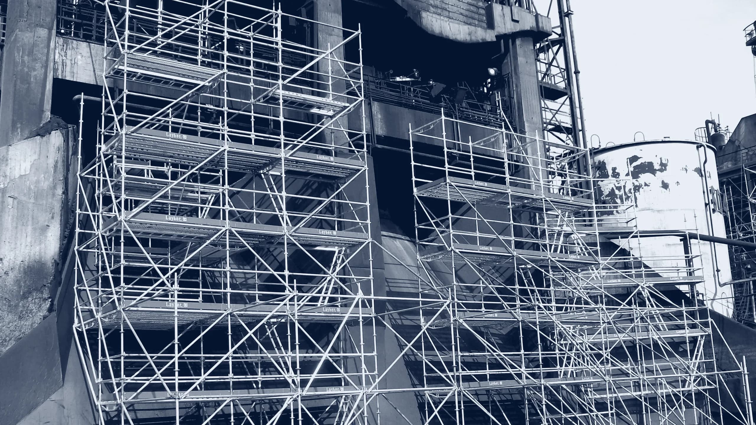 Plataformas del sistema Layher escalando la fachada de una instalación industrial