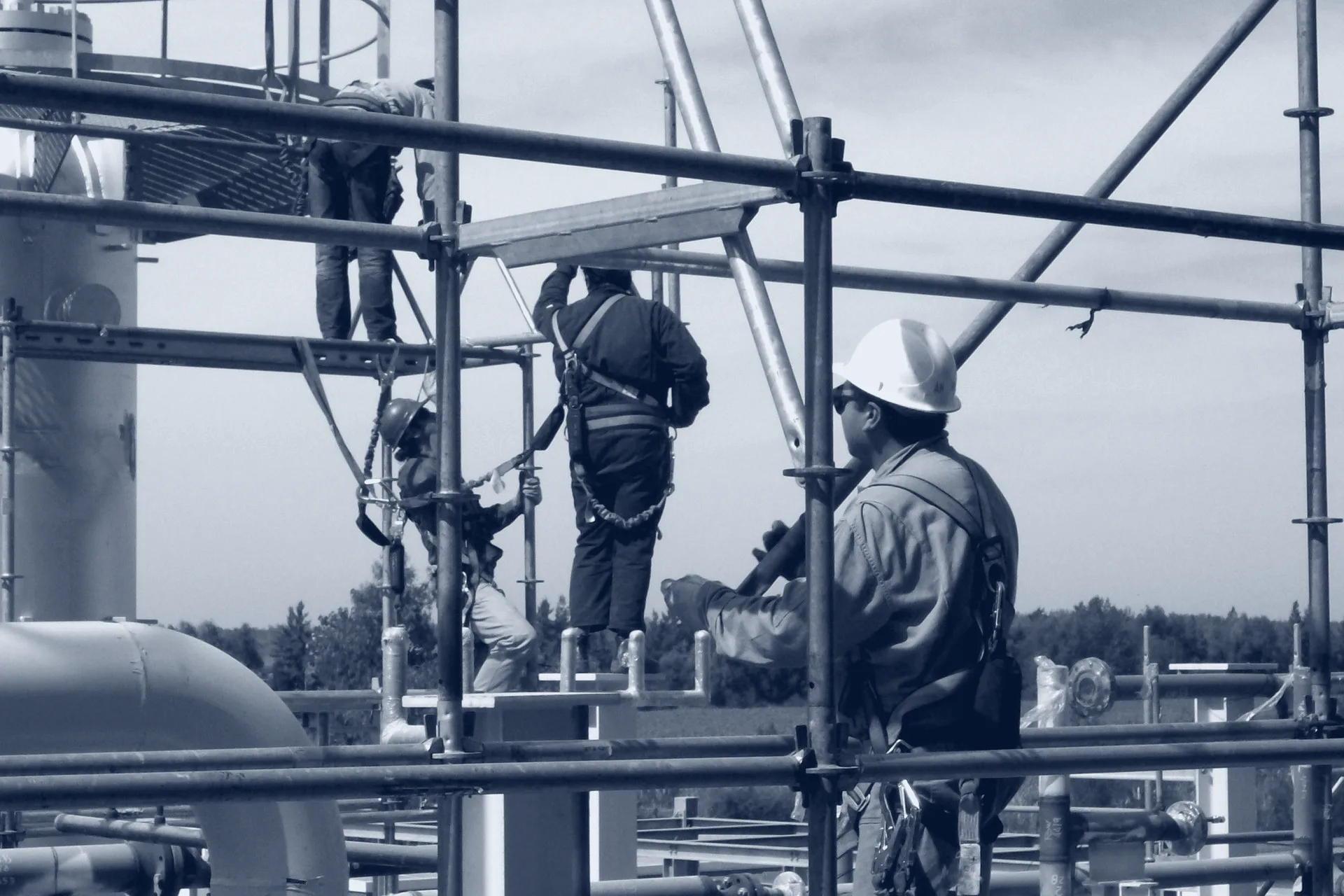 Operarios con arnés y chaleco salvavidas sobre una estructura montada sobre el agua
